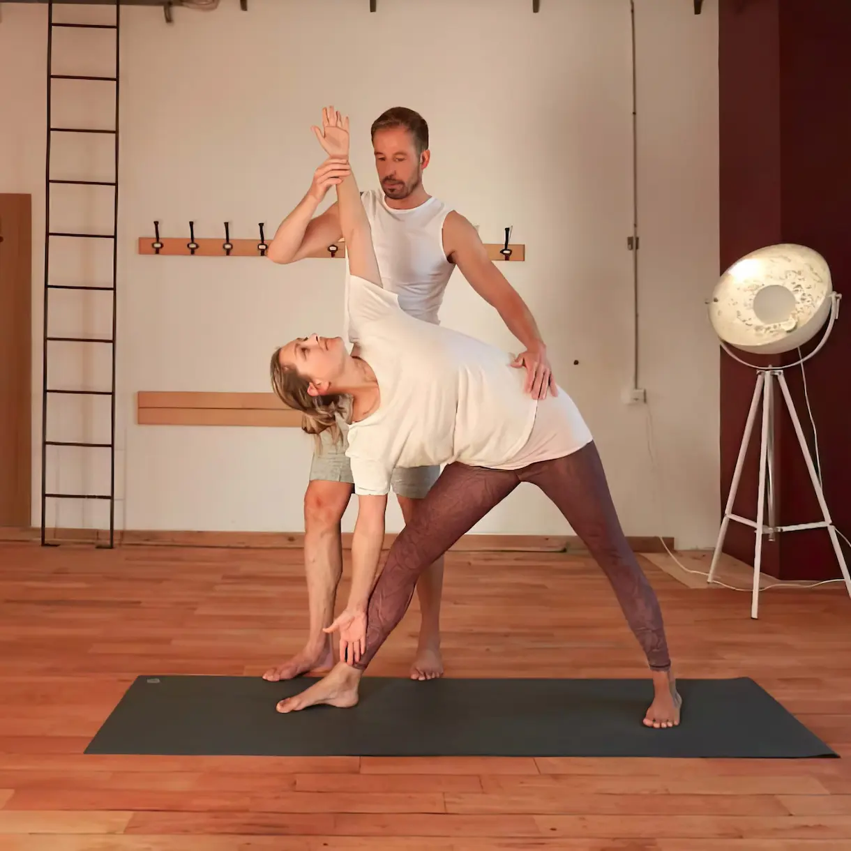 Yoga-Vorarlberg-Coach Christoph Hiebl begleitet eine Studentin bei einer Pose.